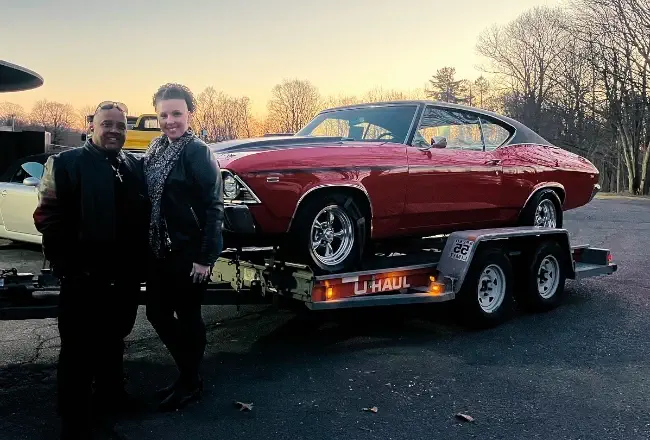 New car owner smiling in front of luxury vehicle from Buonauto Enterprises
